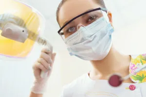 masked hygienist with dental tools 